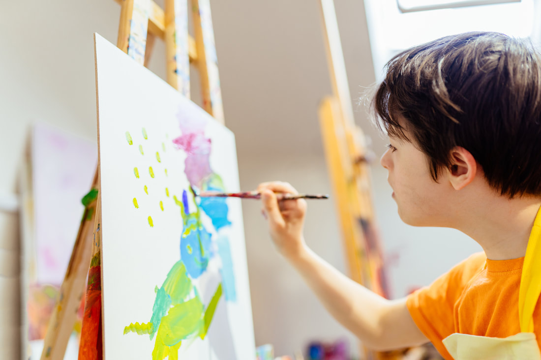A picture of a child painting a colorful, abstract picture